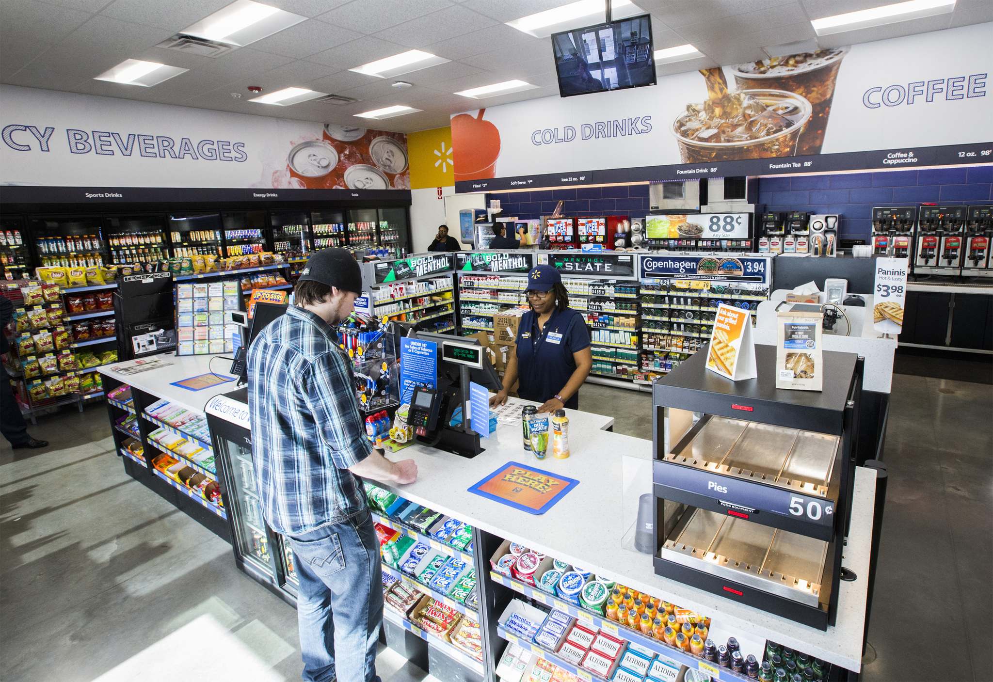 A store associate at a checkout while a customer stands beside the counter.